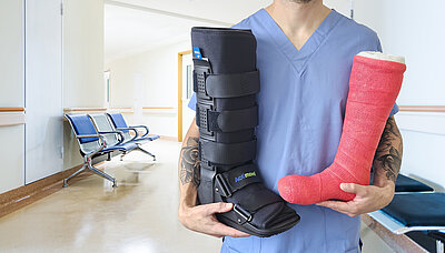 Healthcare Professional holding a cast boot and a red foot cast